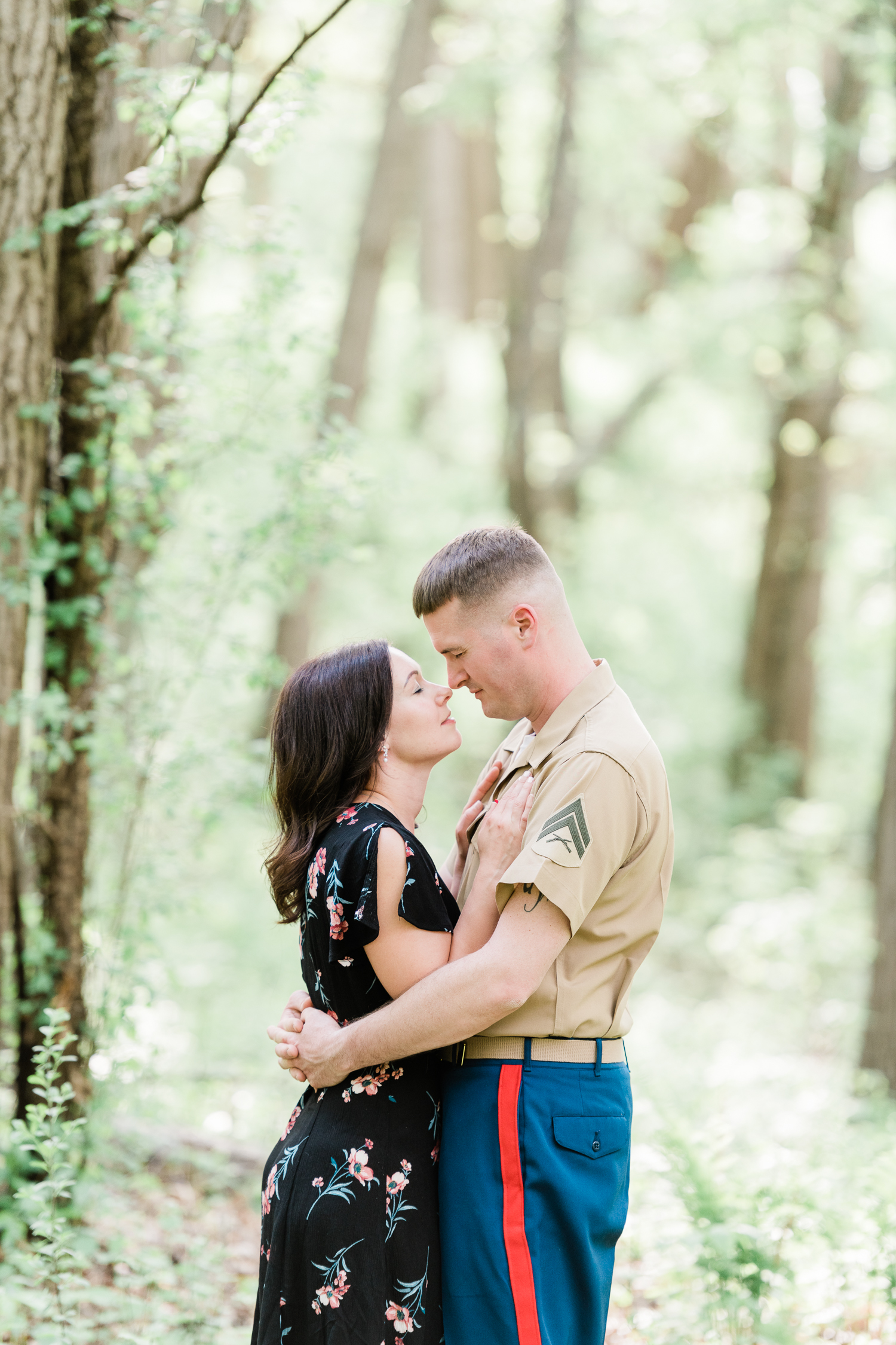 Engaged couple in black floral dress and military uniform hugging and looking at each other at Nagawaukee Park