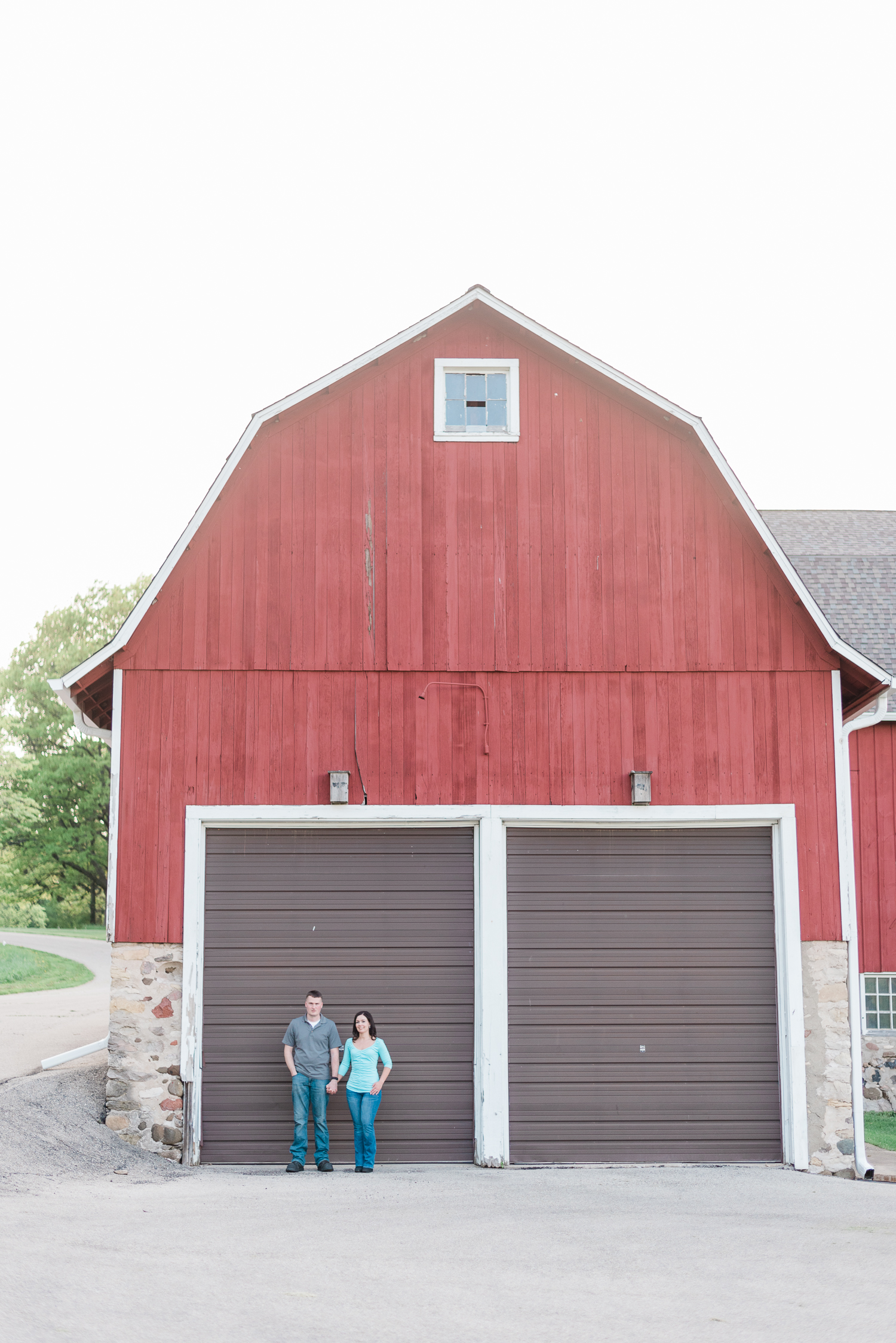 Engaged couple holding hands at a red barn