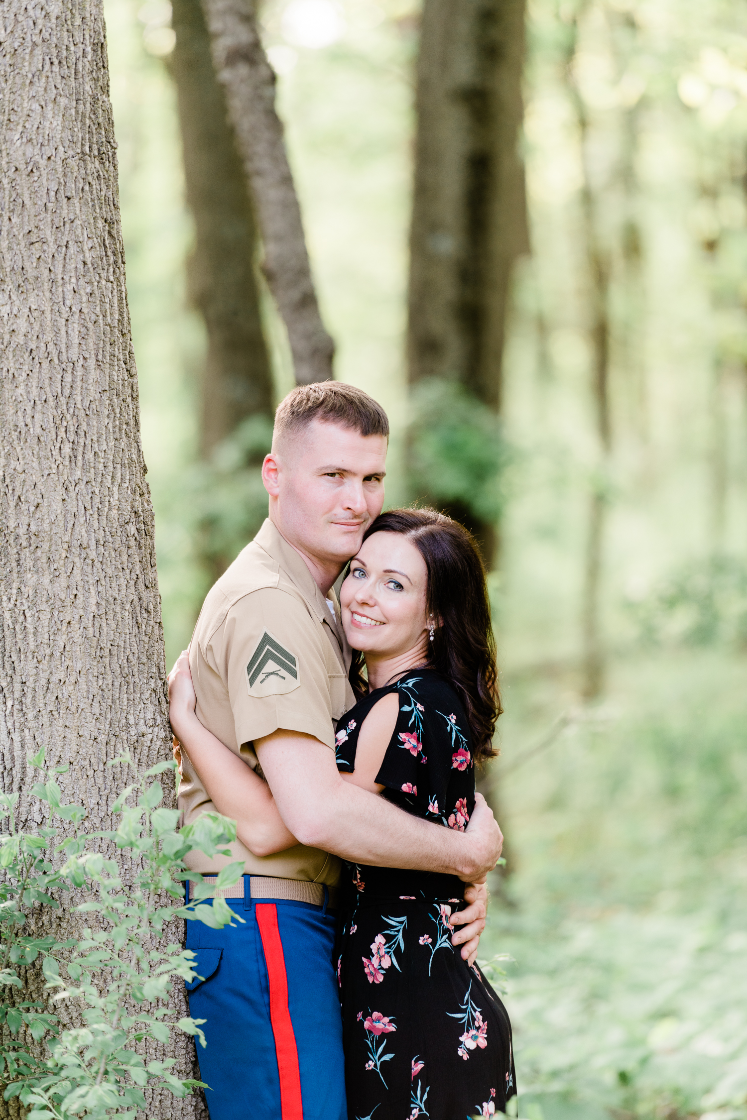 Engaged couple in black floral dress and military uniform hugging and looking at each other at Nagawaukee Park