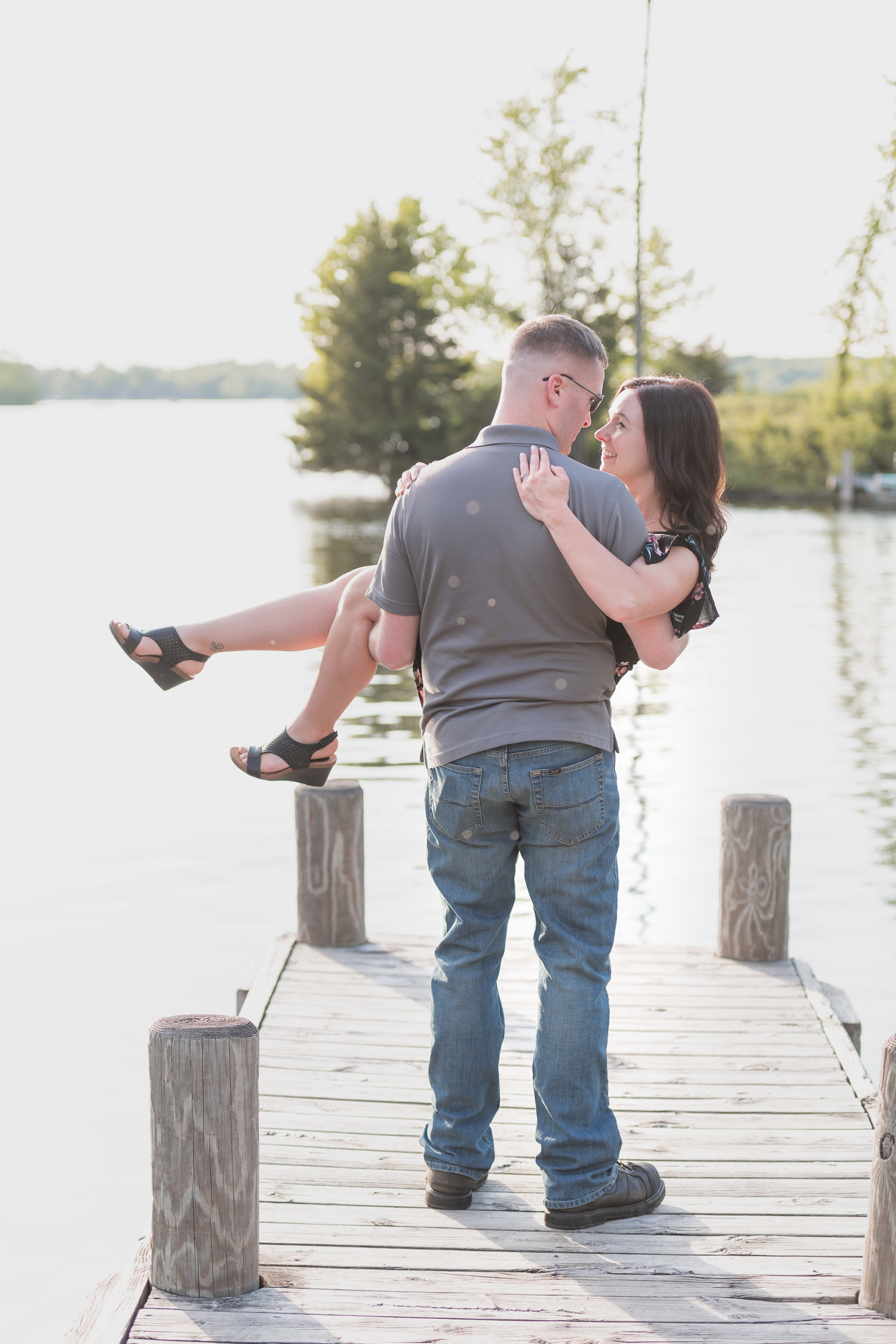 Guy lifts girl at the edge of a boat dock in Nagawaukee Park