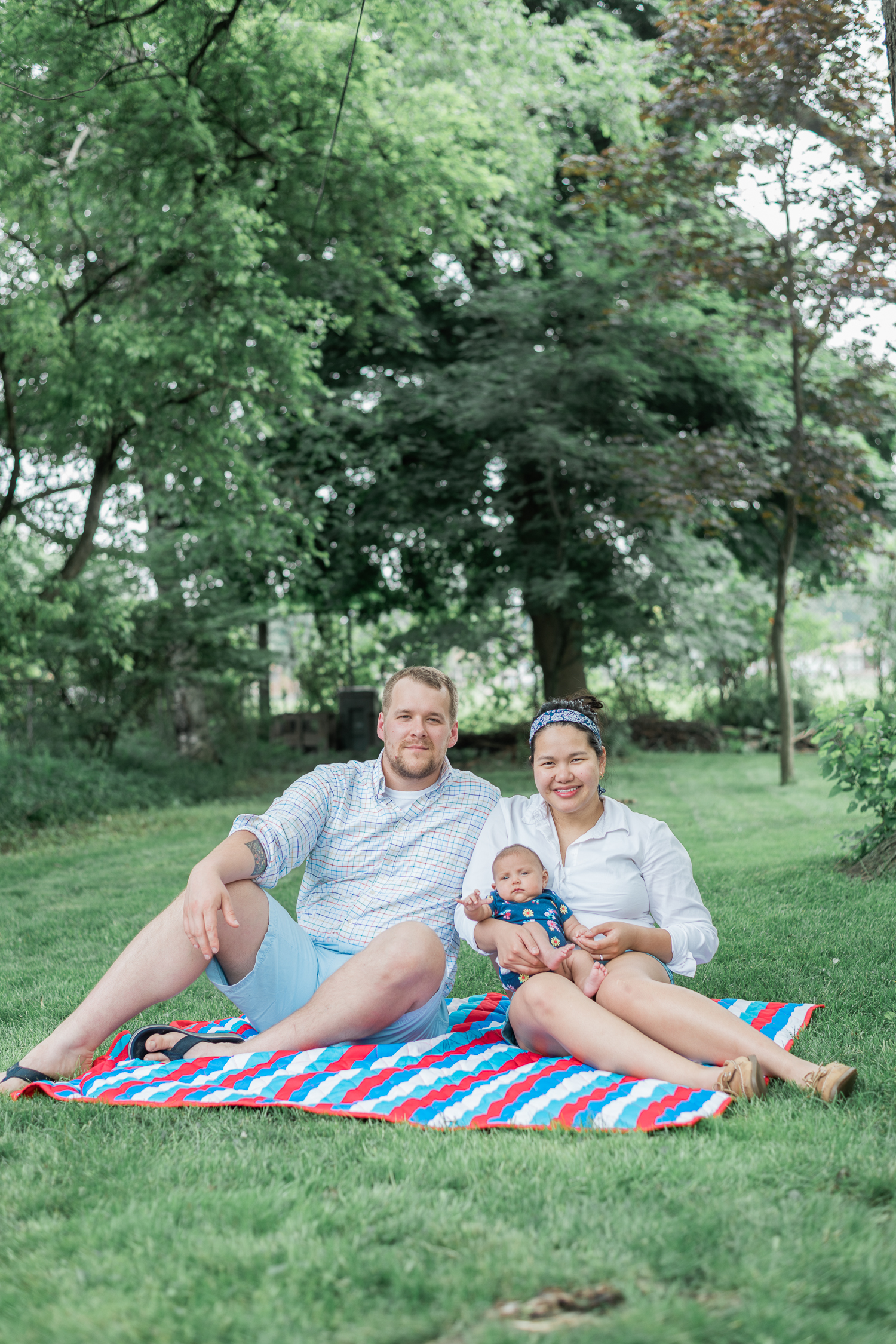 Family with newborn sitting on a picnic blanket on their backyard