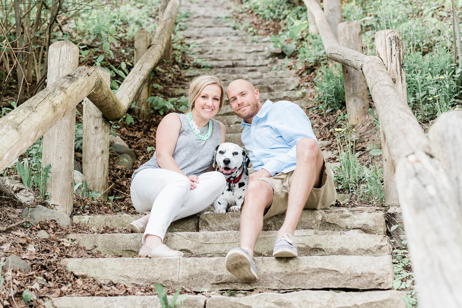 Engaged couple sits down with their Dalmatian at Lake Park