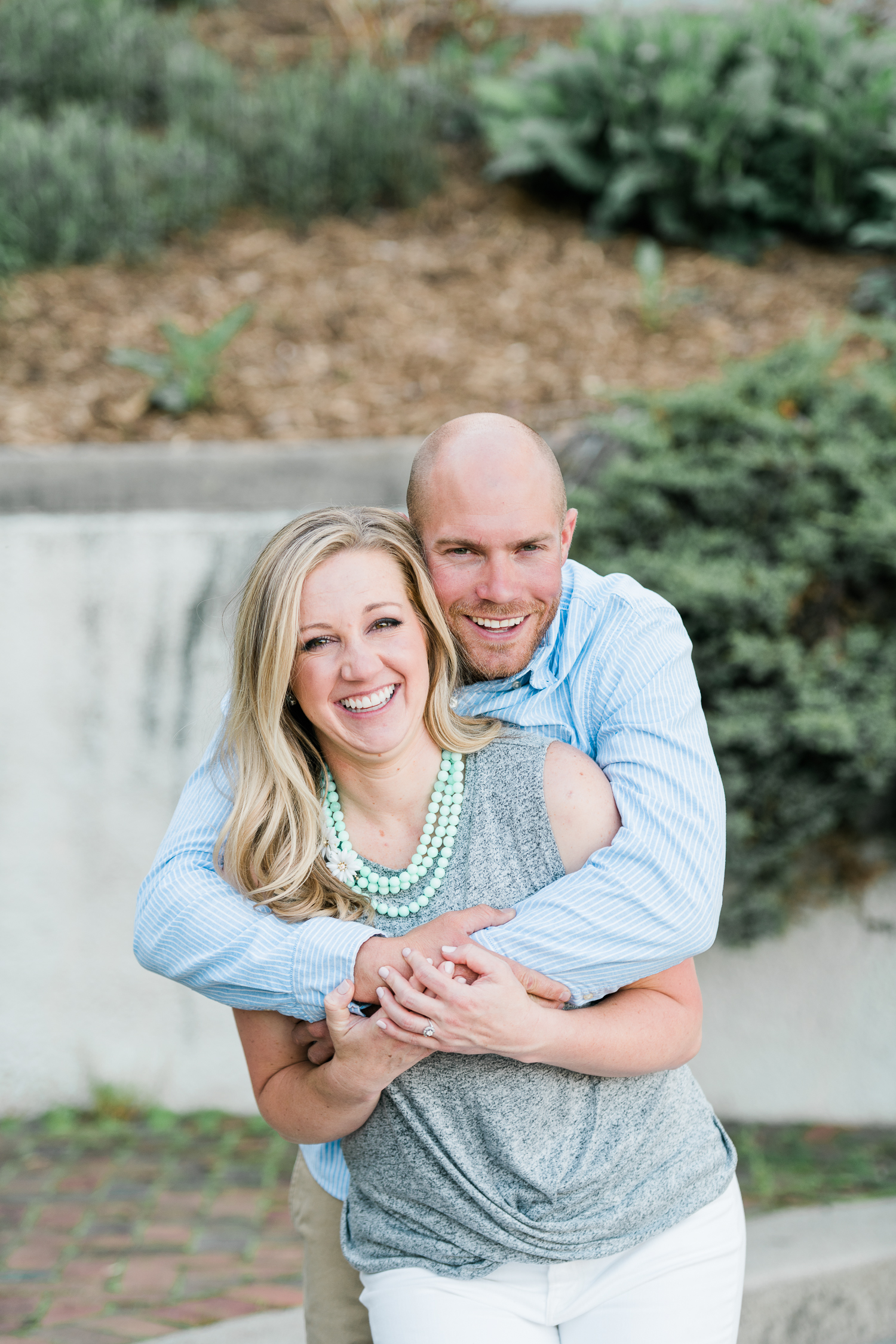 Engaged couple in gray and light blue hugging tightly while smiling