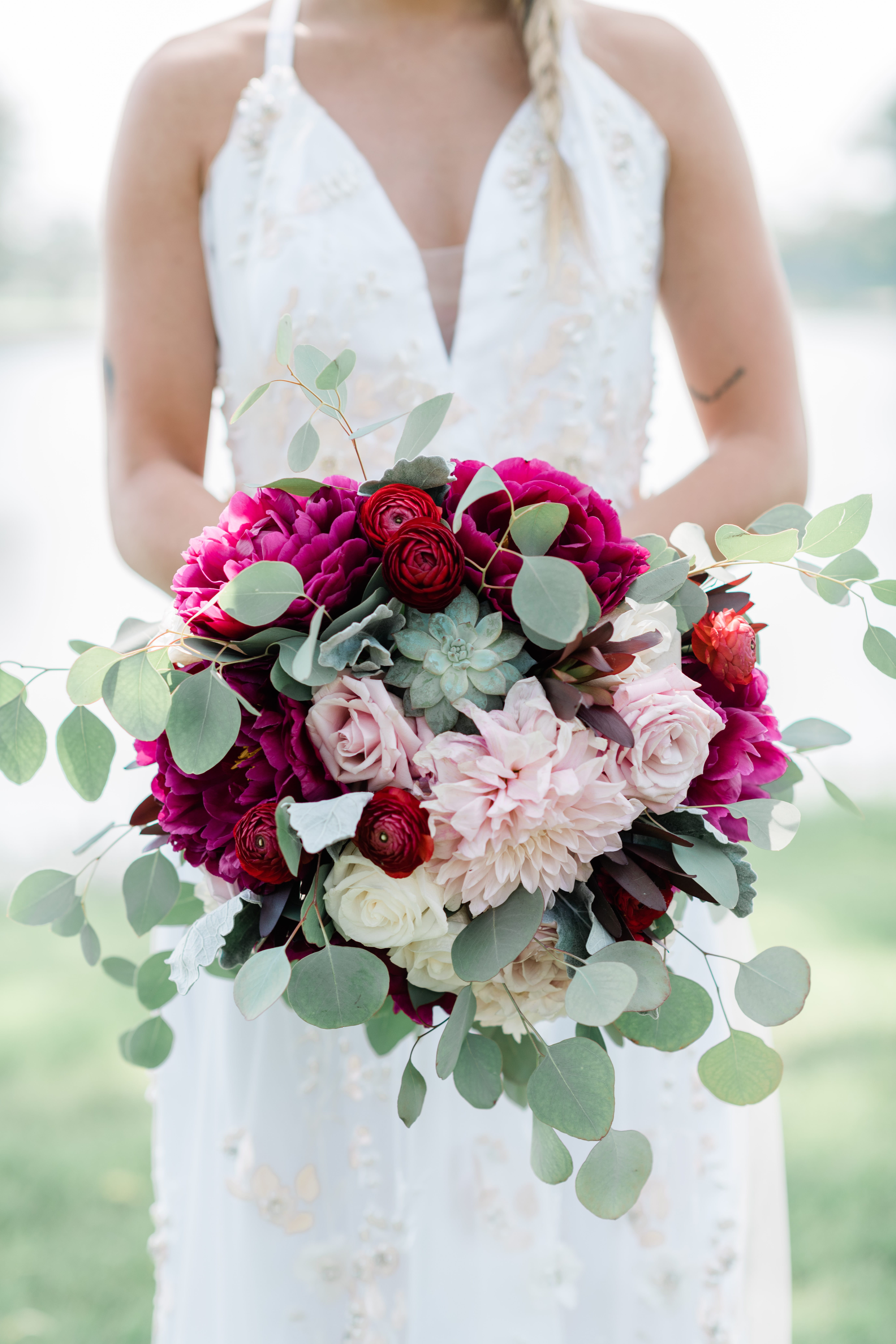 Bridal bouquet made with red, pink, purple and white flowers with greenery