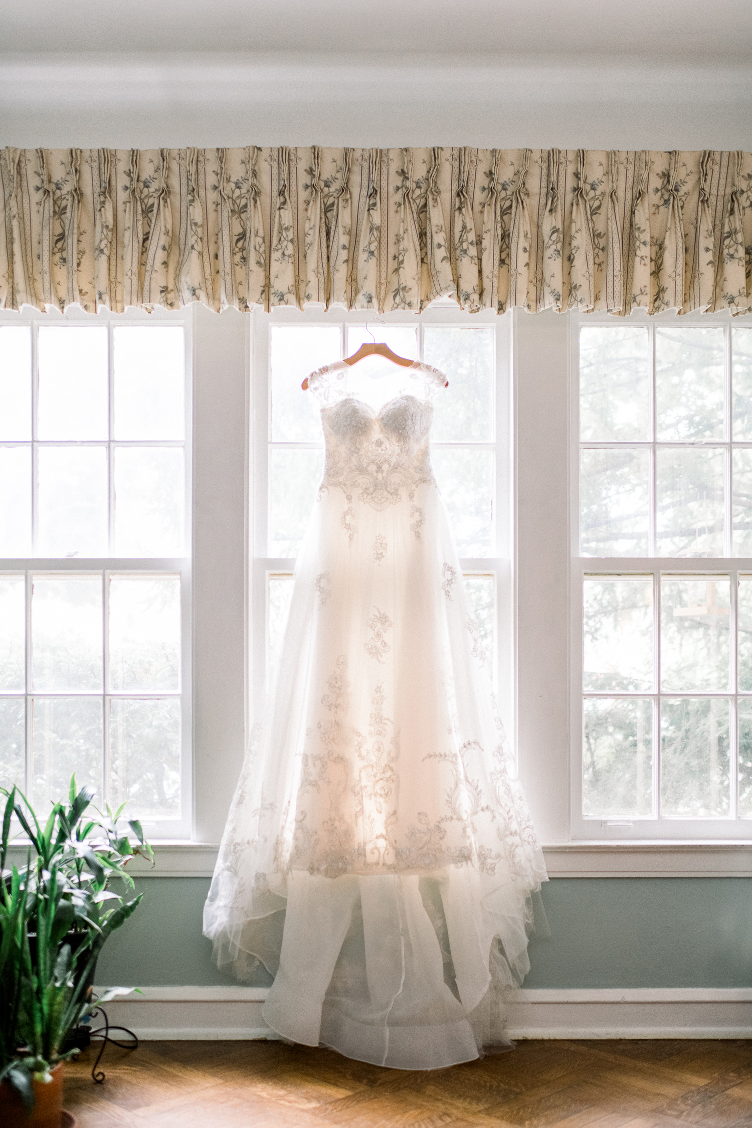 White lacy wedding dress hanging by the window