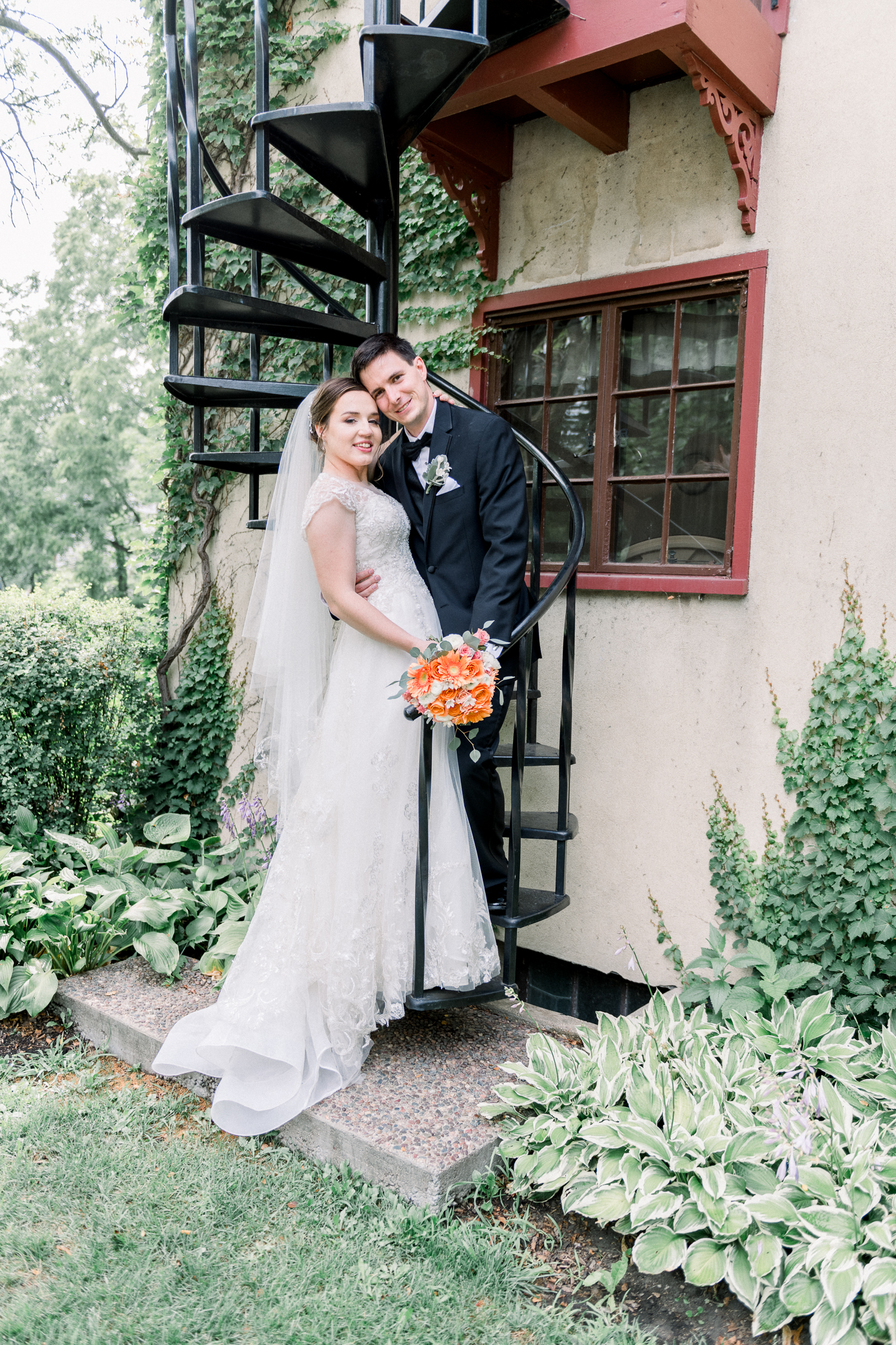 Bride and groom pose by a spiral staircase