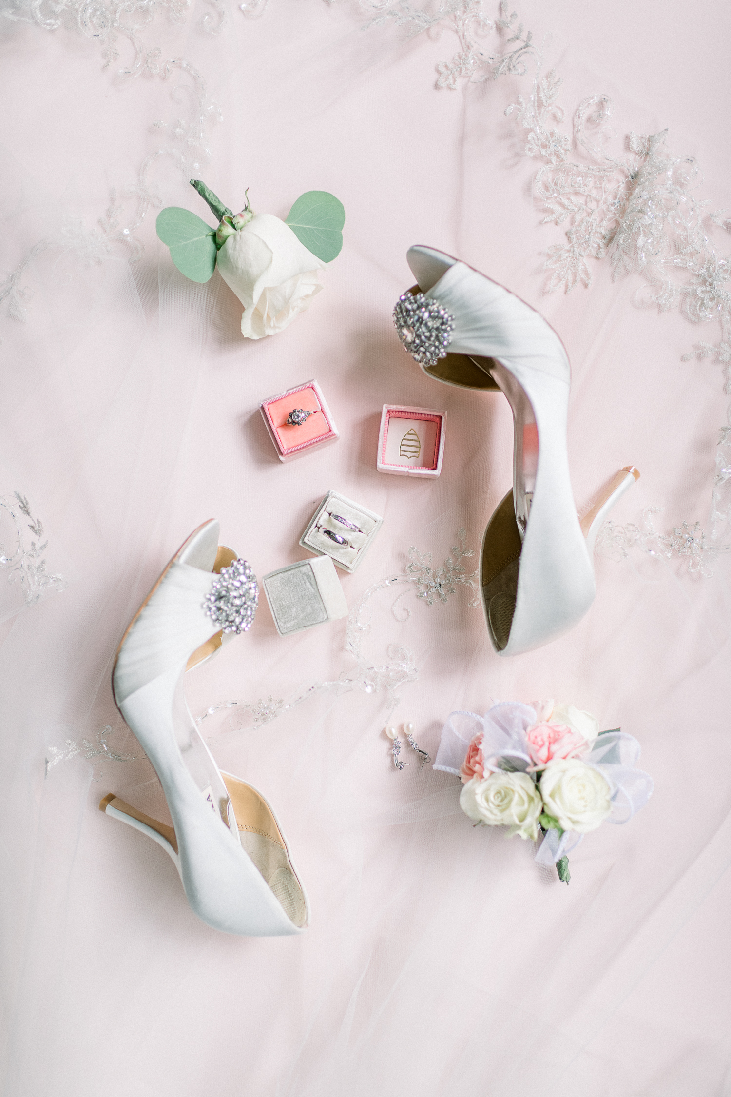 Flat lay styling of wedding details with shoes, rings, ringbox and corsages