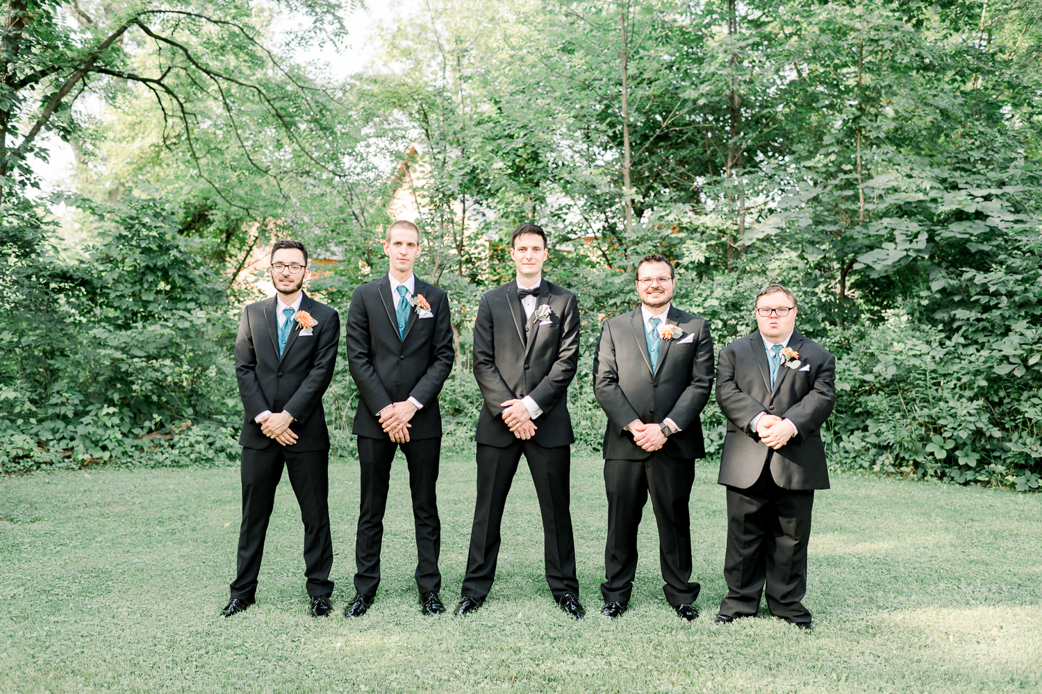 Groomsmen and groom lined up in a park