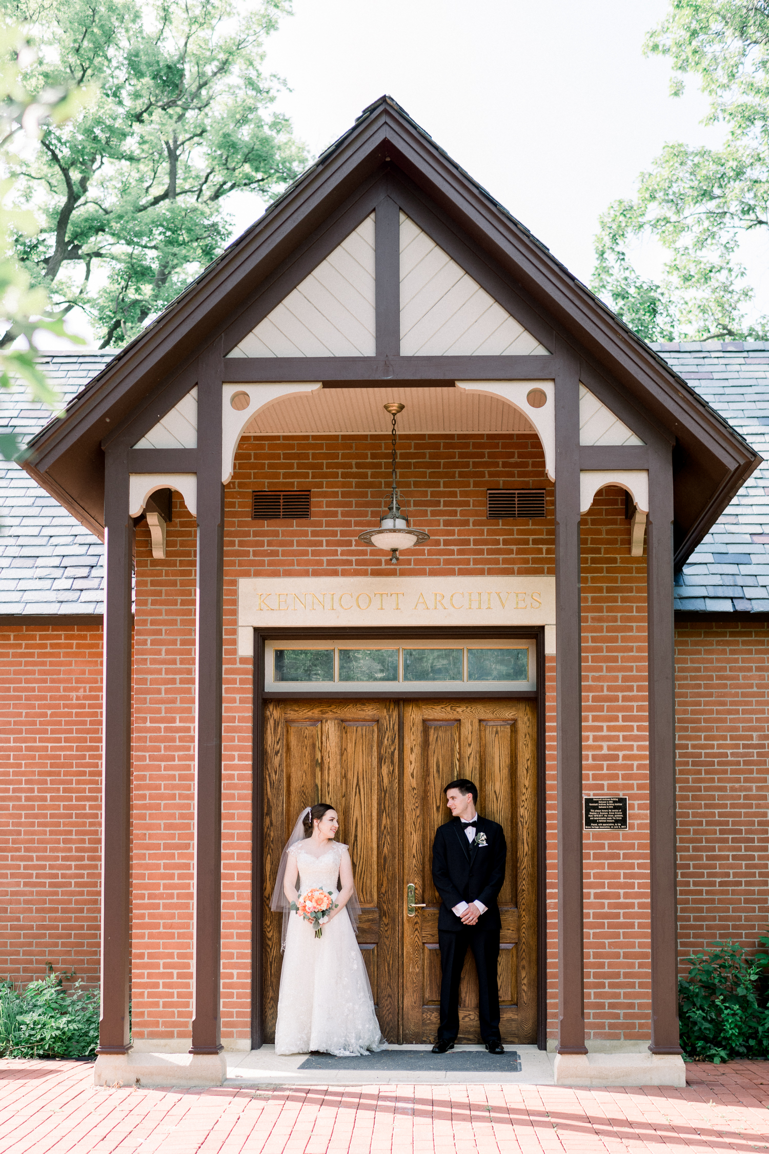 Bride and groom looks at each other standing in front of a wooden door of a browstone