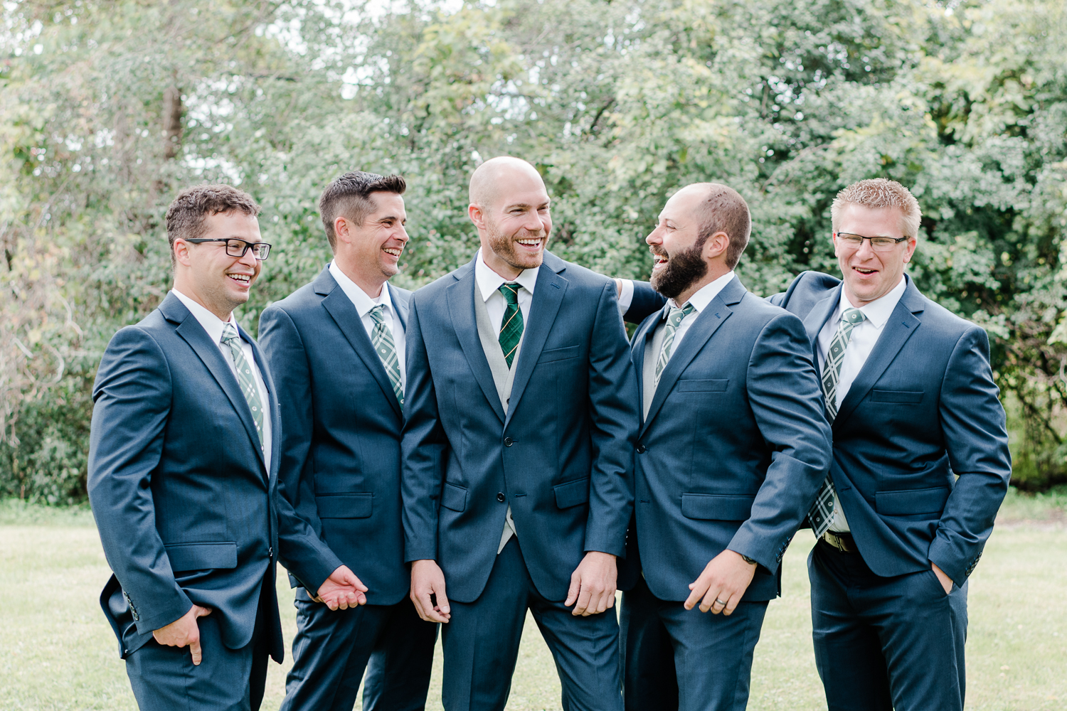 Groom with groomsmen in blue suits smiling at each other