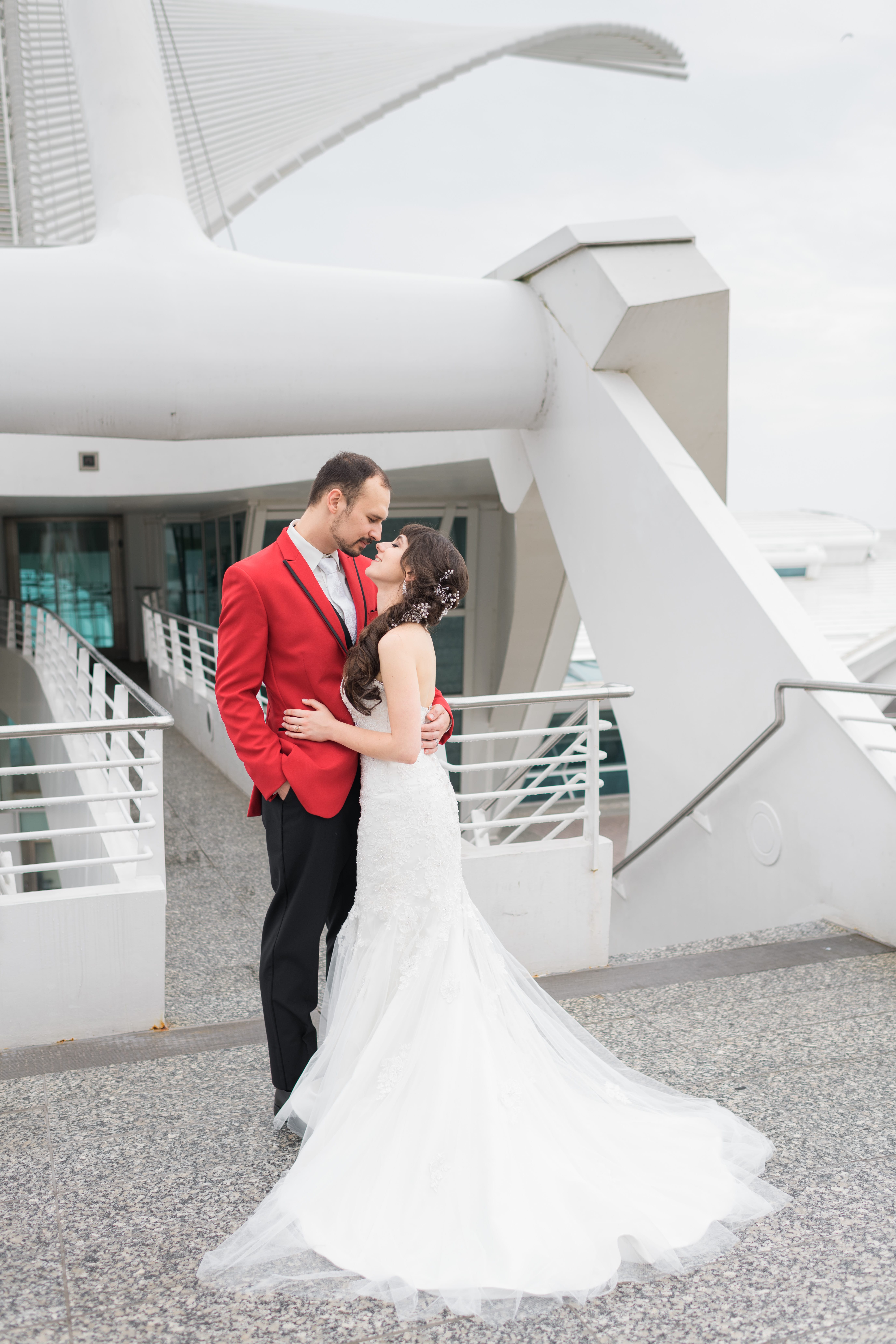 Bride and groom looks at each other posing in from of Milwaukee Art Museum