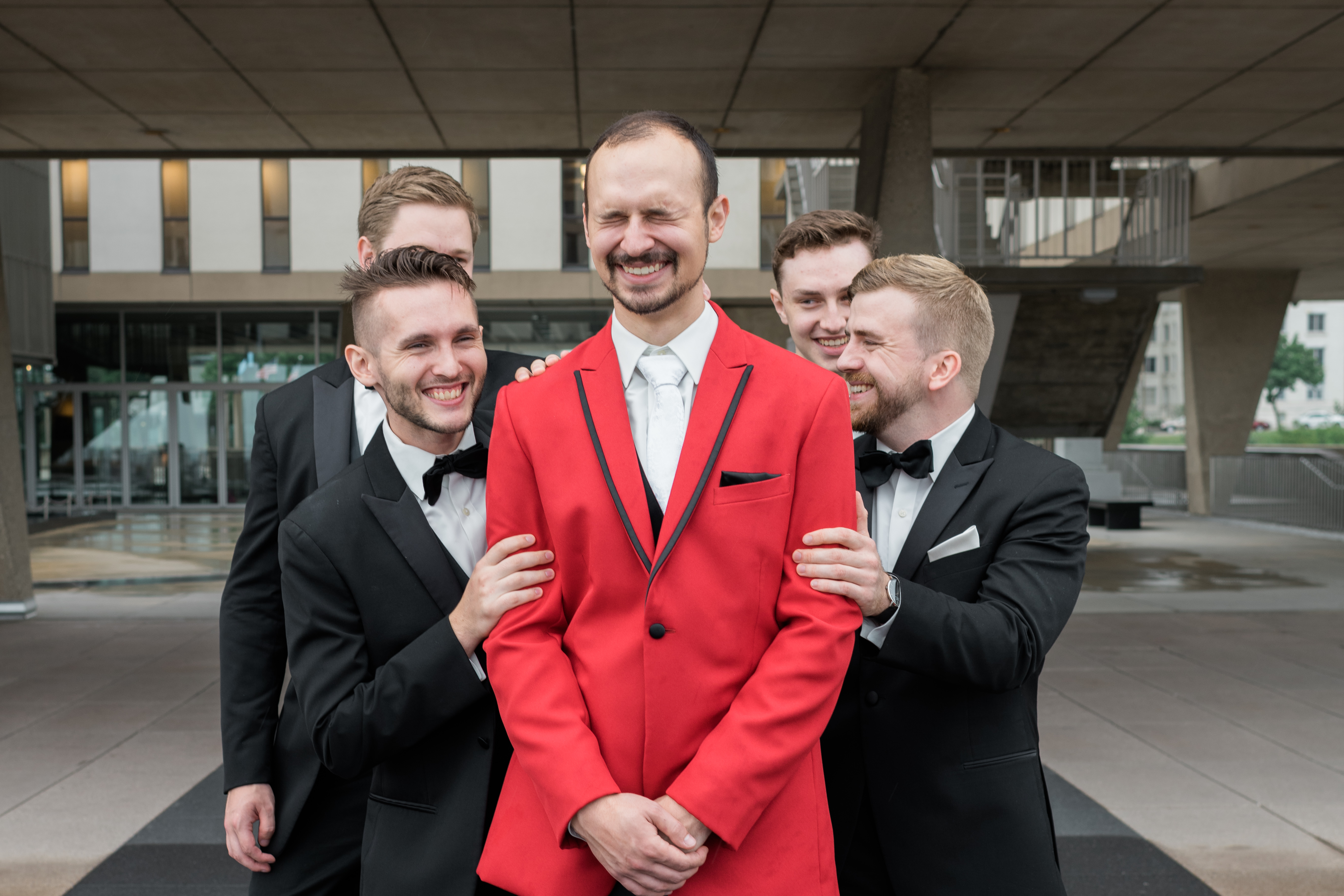 Groomsmen make groom laugh during bridal party photo