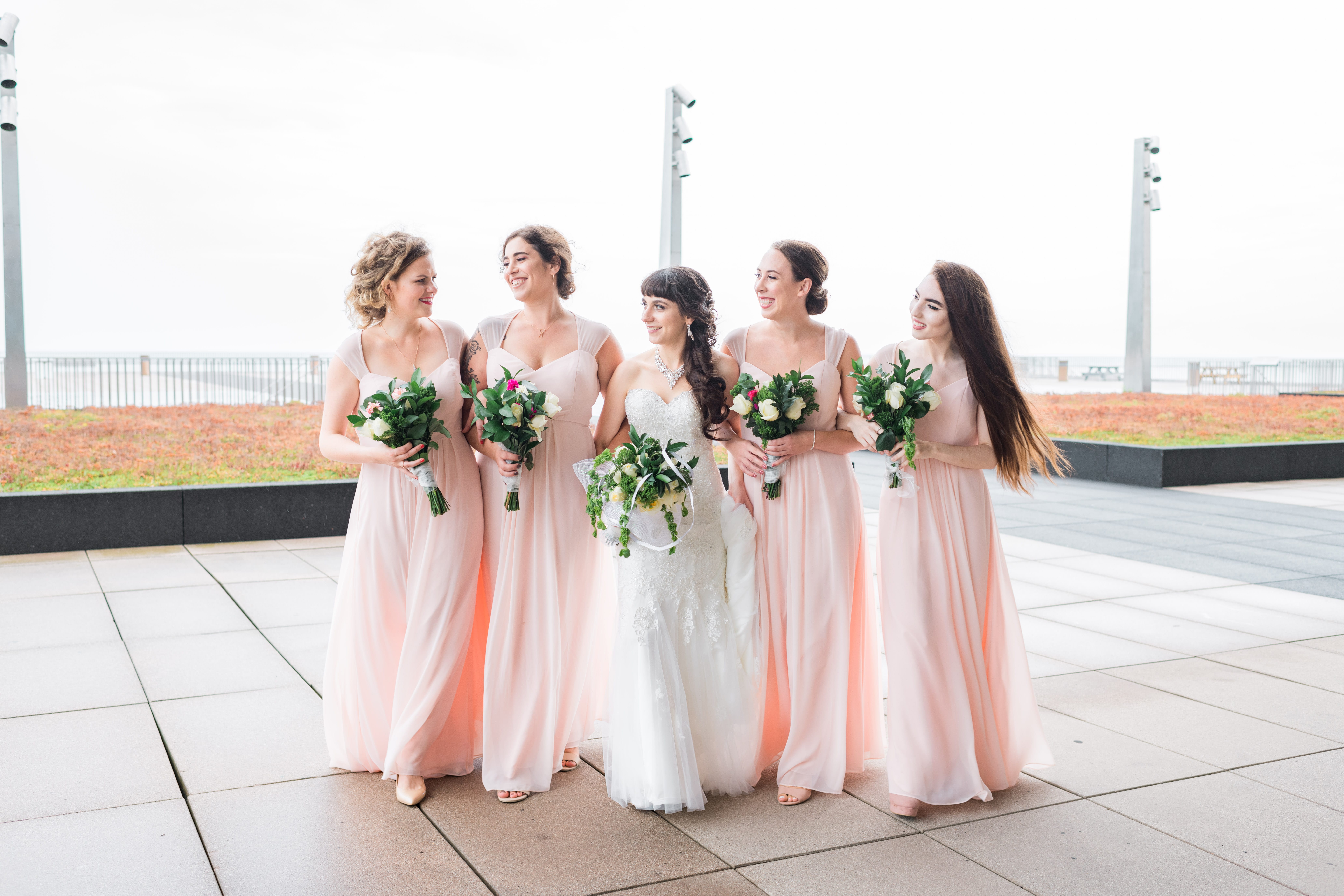 Bride and bridesmaids walking while talking to each other towards the camera