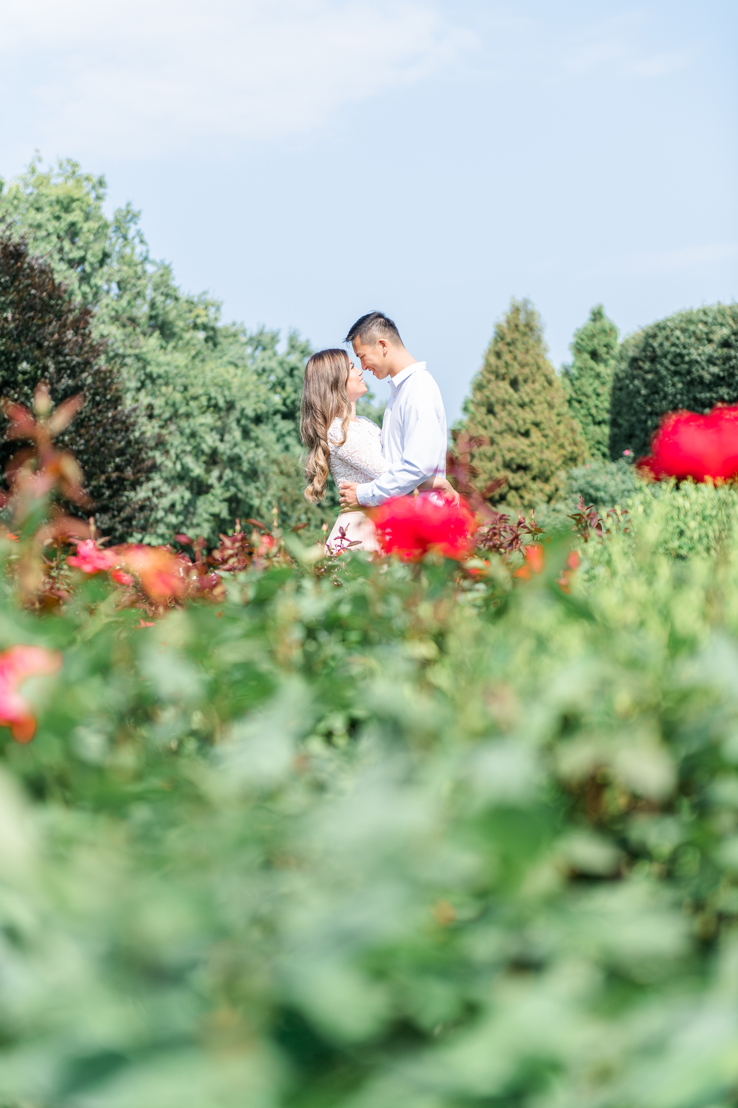 Engaged couple looking at other while hugging in with greens and flowers everywhere at Chicago Botanic Garden