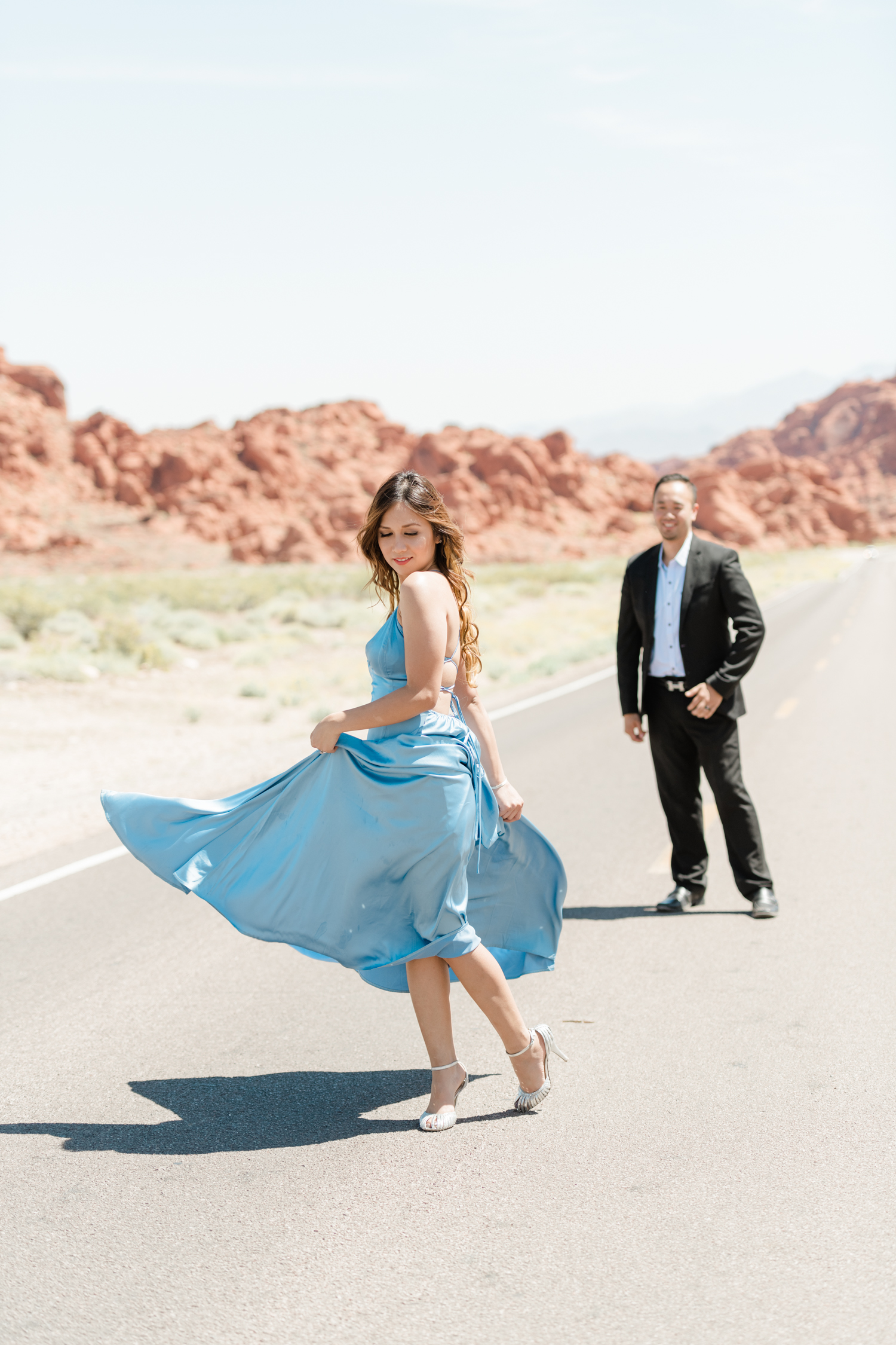 Girl show off her long blue dress as boy looks on for Las Vegas Engagement