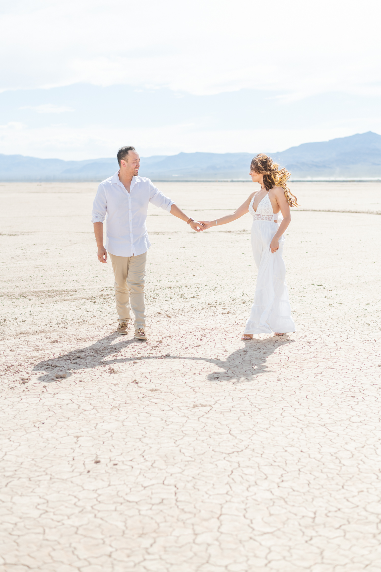 Boy and girl in white outfits walks hand in hand for their Las Vegas Engagement session