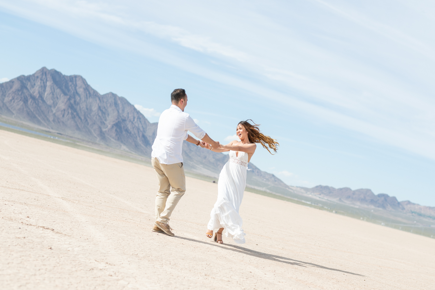 Boy and Girl in white outfits spin around playfully in the dessert