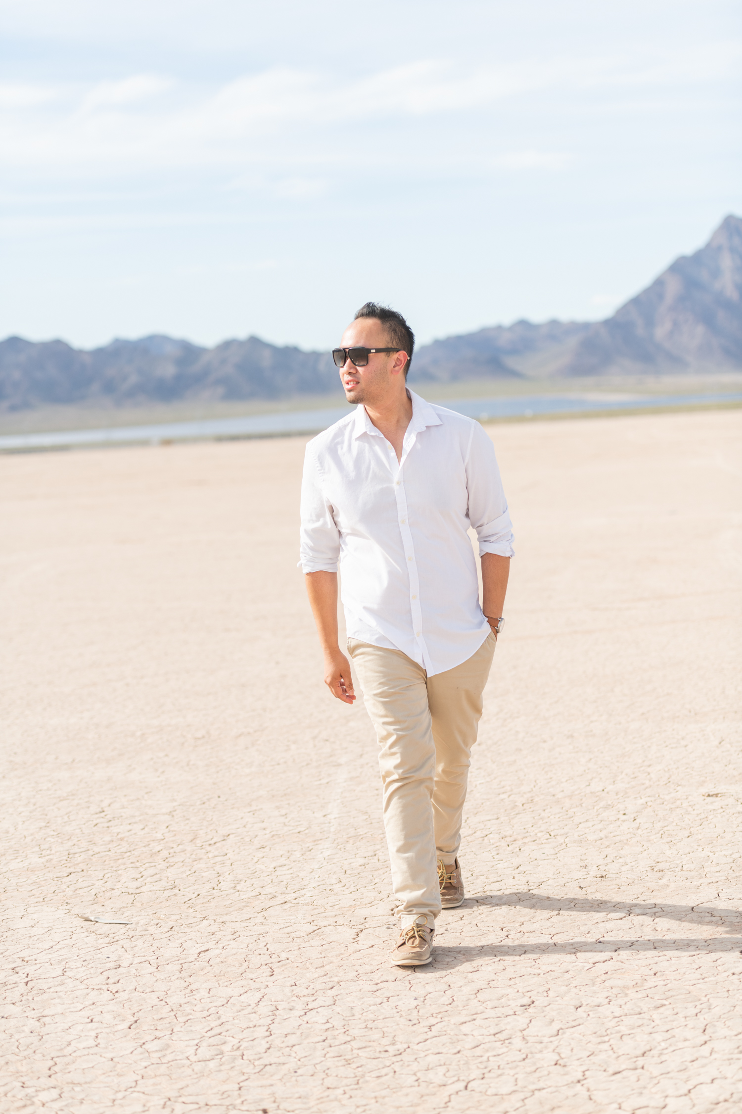 Boy with sunglasses in white shirt and khaki pants walking through a dry lake bed
