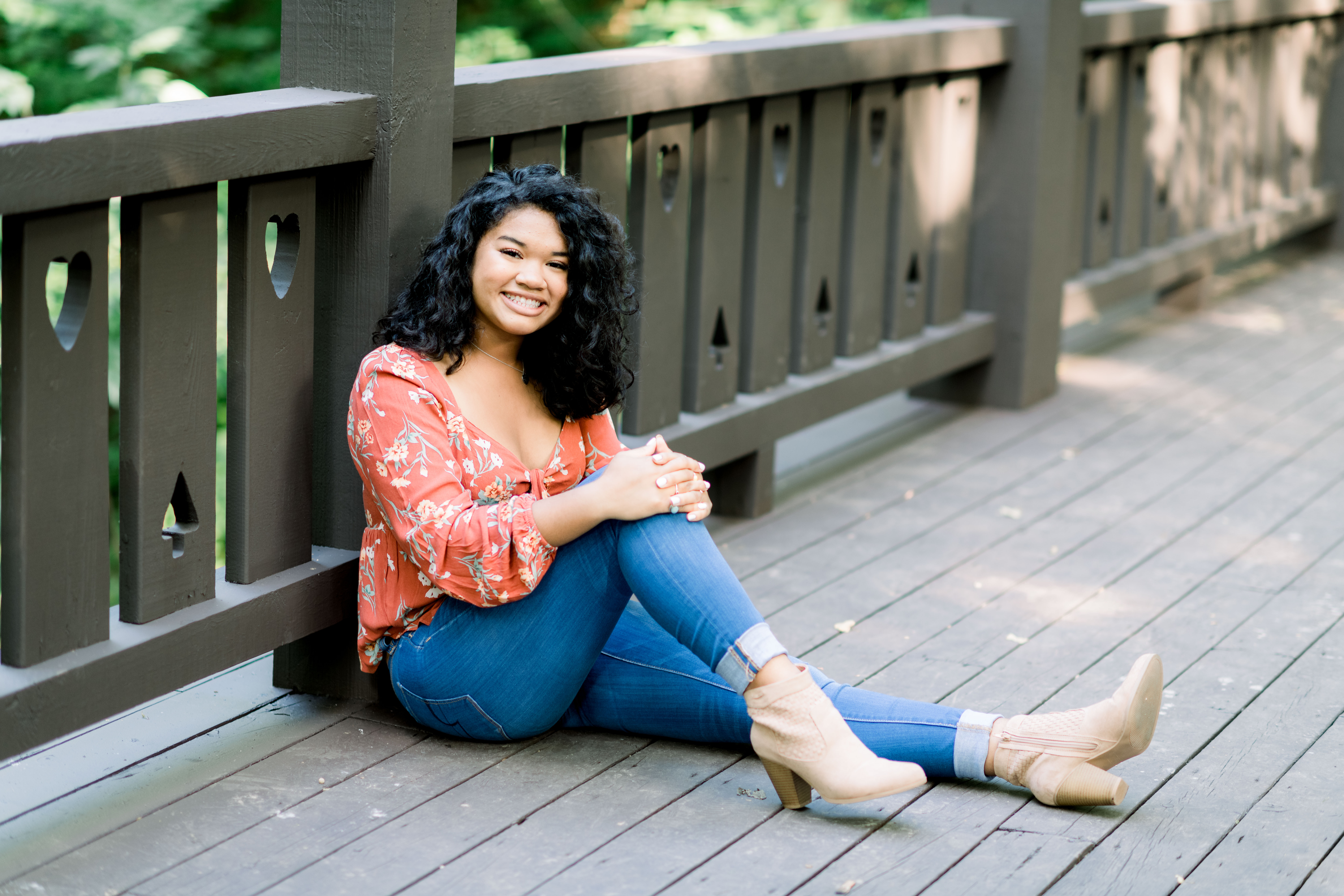 Girl in jeans sitting against the bridge during a senior portrait session