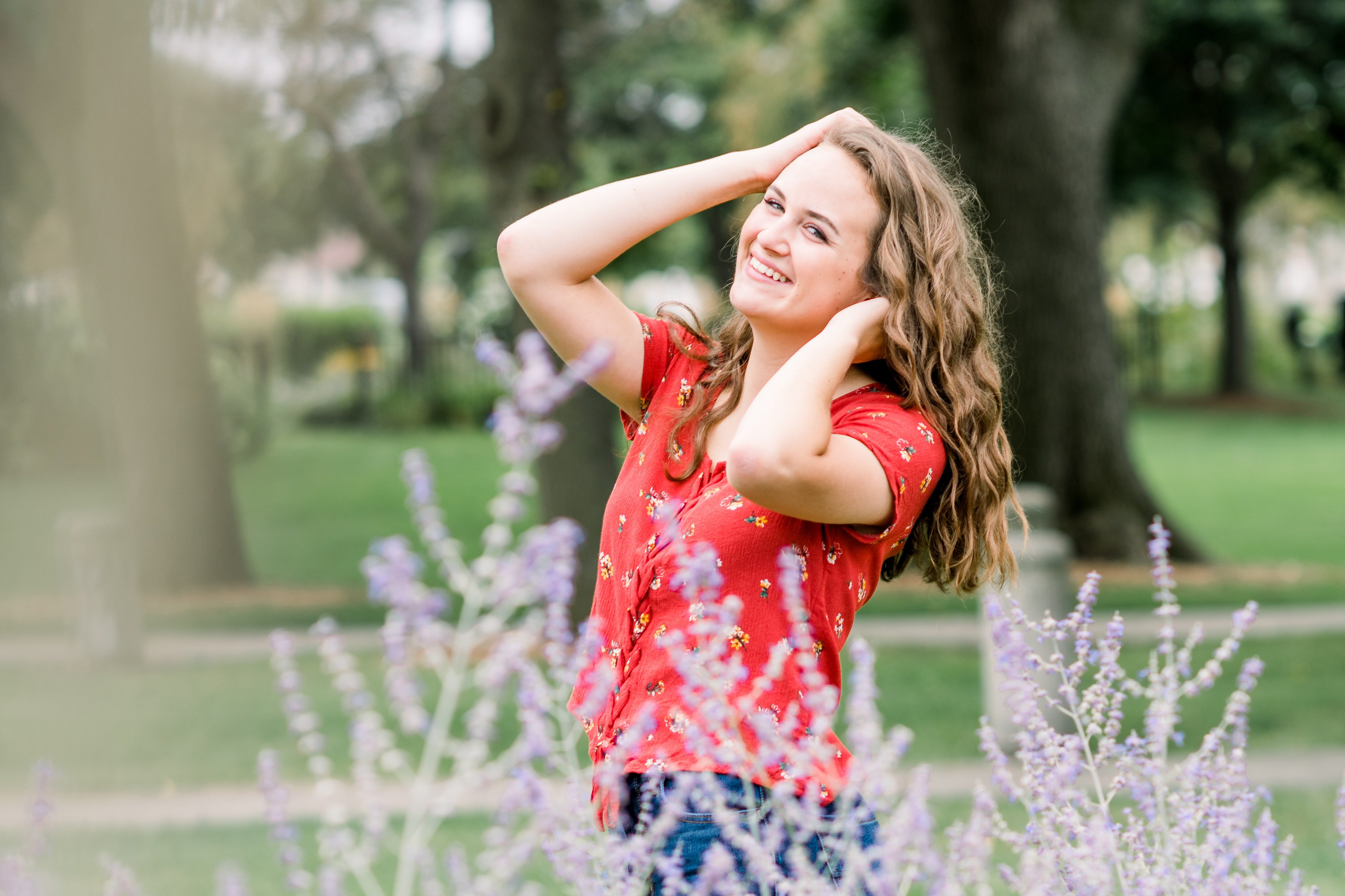 Girl in a red floral top playing with her hair during a senior session