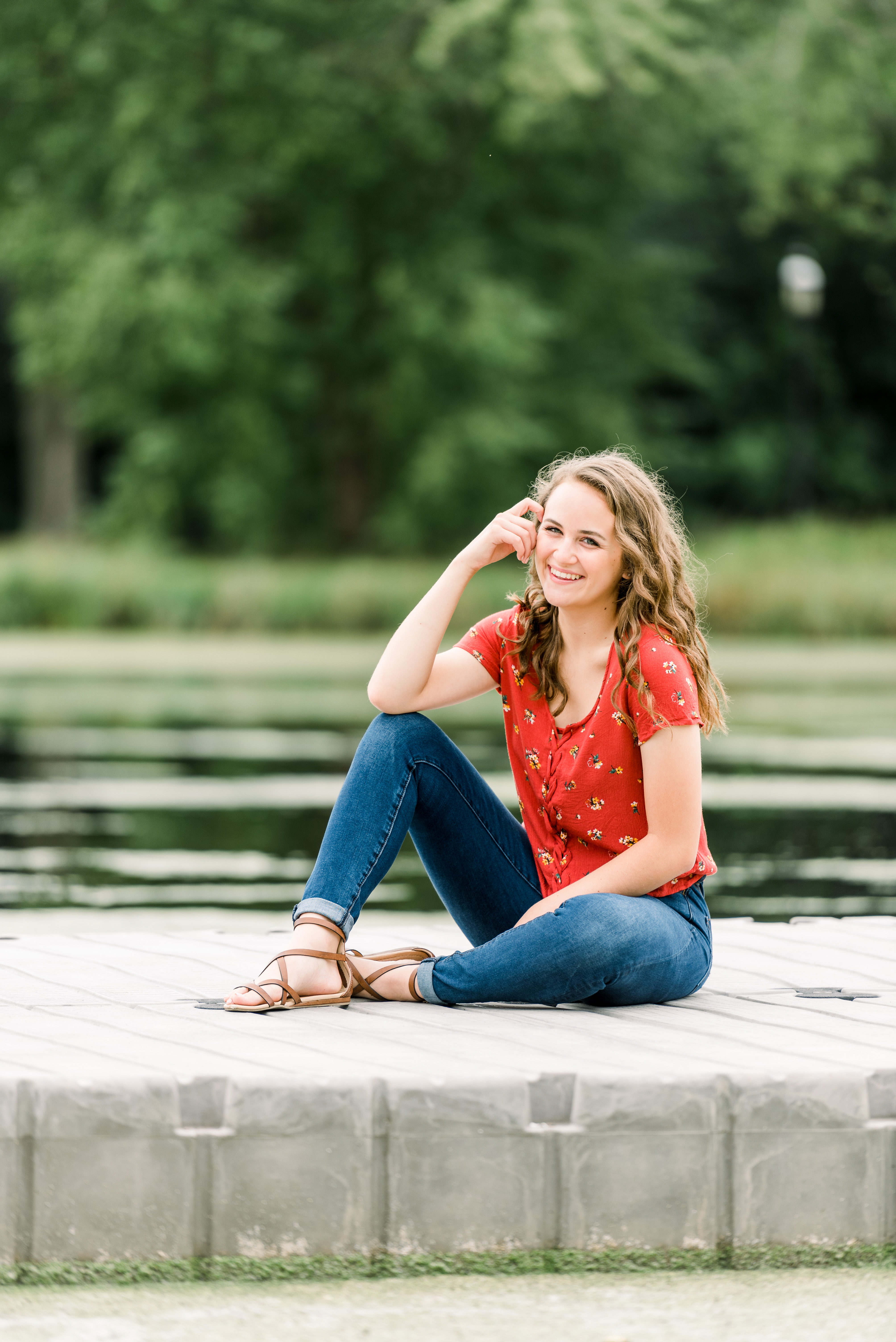 Girl in red floral top and blue jeans sitting on a boat ramp