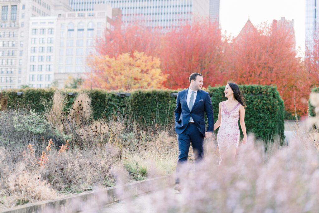 Couple walking along Lurie Garden in Millennium Park Chicago with red trees in the background