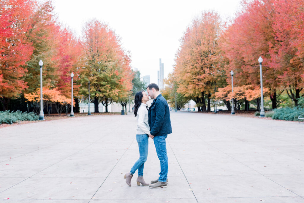 Couple almost kissing at Lurie Garden in Millennium Park Chicago with red trees in the background