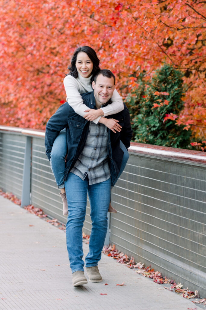 Couple playing around Lurie Garden in Millennium Park Chicago with red trees in the background